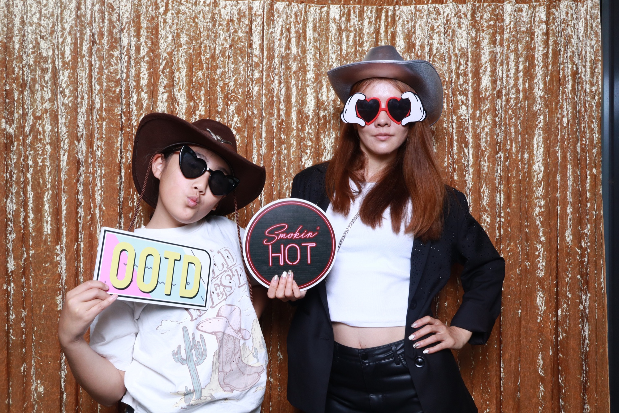Guests posing with photo booth props against a gold sequin backdrop