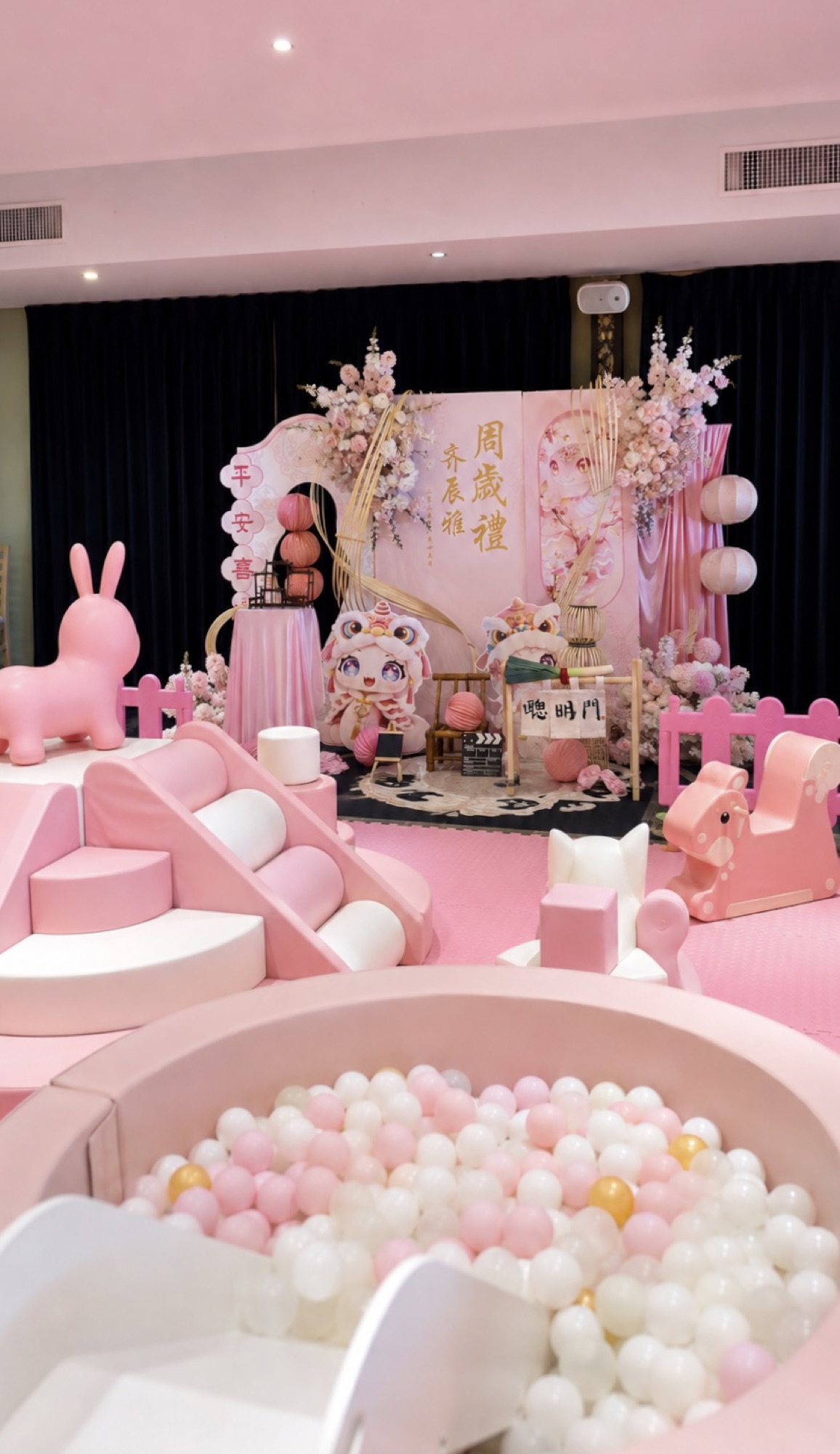 Pastel pink birthday backdrop with ball pit and themed props